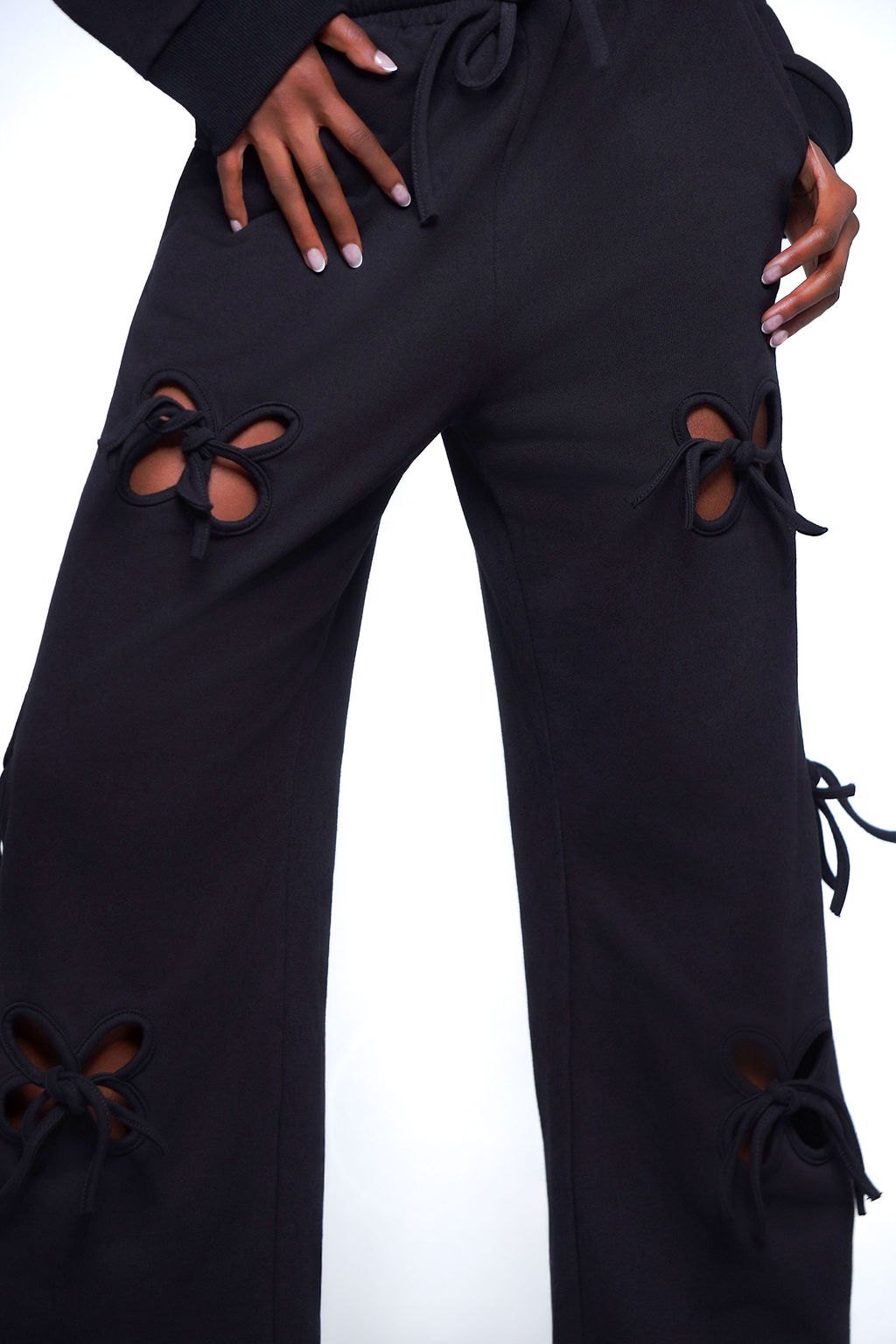 Dark Side Distressed Set in black — long sleeve distressed cutout sweatshirt with matching wide leg jogger pants, styled with platform sandals and yellow sunglasses,