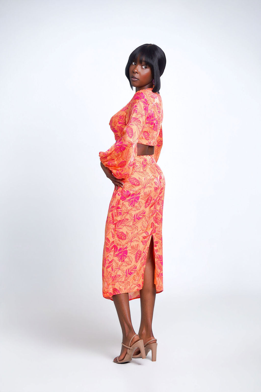 Island Twist Midi Set in orange and hot pink tropical leaf print — long sleeve twist knot crop top with balloon sleeves and matching wrap midi skirt with ring waist detail